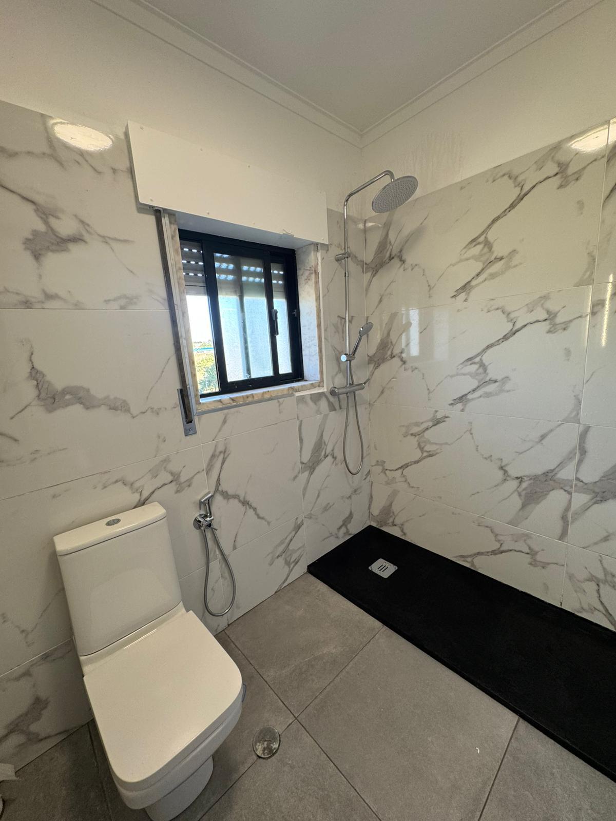 Casa de banho em mármore com janela e base de duche preta